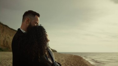 Romantik çift deniz sahilinde birbirlerine sarılıyorlar. İki aşık sahilde buluşuyor.