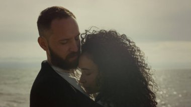 Gençler dışarıda kucaklaşıyorlar. Deniz kıyısında kucaklaşan evli bir çift..