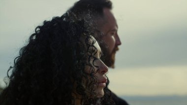 Etnik çift dışarıda günbatımının tadını çıkarıyor. Karışık ırk insanları deniz manzarasına bakar..