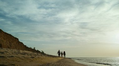 Deniz manzaralı sahilde yürüyen aile siluetleri. Tatil gevşeme kavramı.