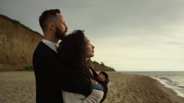 Güzel aşıklar deniz kıyısında birbirlerine sarılıyorlar. Çiftler doğanın tadını çıkarır.