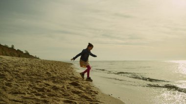 Sabahları deniz kıyısında koşan tatlı bir çocuk. Sahildeki dalgalardan uzaklaşan neşeli kız.