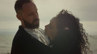 Genç çift romantik bir randevuda kumsalda flört eder. Güzel insanlar deniz kenarındaki kıvırcık saçlara dokunur.