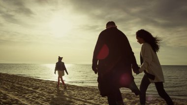Sakin insanlar günbatımı deniz sahilinde tatilin tadını çıkarırlar. Aile sevgisi doğa huzuru.