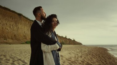 Tatilde sahilde kucaklaşan bir çift. Mutlu melez aşıklar okyanus kıyısında sarılırlar