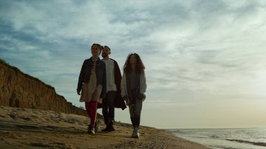 Anne ve babası kumsalda beraber yürüyorlar. İnsanlar deniz doğası manzarasına gidiyorlar..