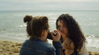 Anne kızı deniz sahilinde fotoğraf çekiyor. Aile sahilde birlikte dinleniyor..