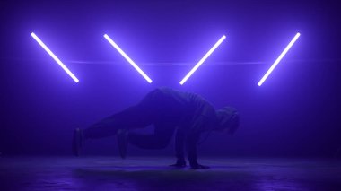 Erkek dansçı ultraviyole ışıkta hip-hop yapıyor. Genç b-boy vücut dönen.