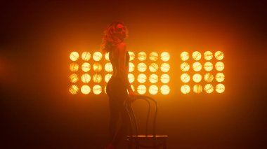 Kız erotik olarak sandalyenin yanında seksi dans ediyor. Kadın şehvetle dans ediyor. 