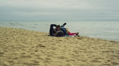 Anne ve babası sakin deniz kenarında tatilin tadını çıkarıyorlar. Aile piknikte oyun oynar..