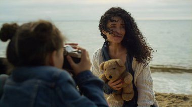 Deniz dalgaları kumsalında fotoğraf çeken sevimli bir aile. Anne baba dışarıda kamera kullanıyor..