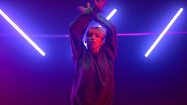 Profesyonel dansçı kız ellerini ultraviyole ışıkta enerjik bir şekilde hareket ettiriyor..