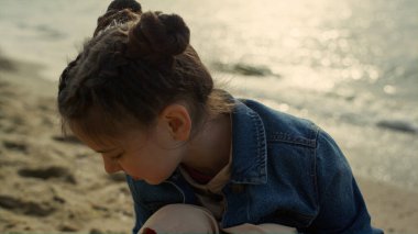 Çocuk deniz kenarında kumsalda oynuyor. Küçük kız okyanus kıyısında eğleniyor..