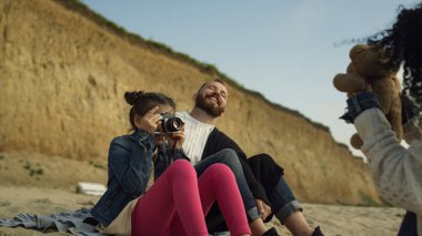 Genç bir aile sahilde eğleniyor. Küçük çocuk güneşli bir günde fotoğraf çekiyor..