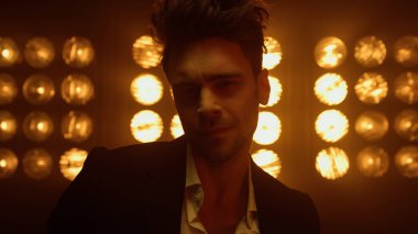 Maço adam gece kulübünün ışıklarında şık kıyafetler giyerek baştan çıkarıcı poz veriyor..