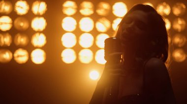 Gece kulübünde mikrofon çalan ateşli bir kadın. Sahnede gösteri yapan kız.