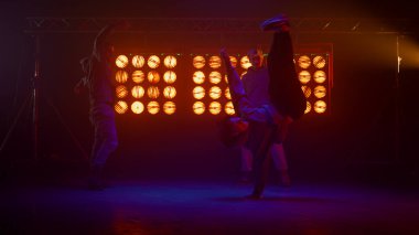 Breakdance ekibi dans pistinde numaralar yapıyor. Siluetler, hip hop takımı sahneye..