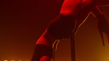 Direğe baş aşağı asılı bir kadın içeride gösteri yapıyor. Direk dansı yapan seksi kız.