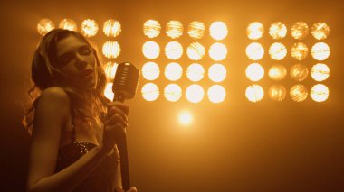 Seksi kadın mikrofonu al ve gece kulübü sahnesinde solo şarkı söylemeye hazırlan..