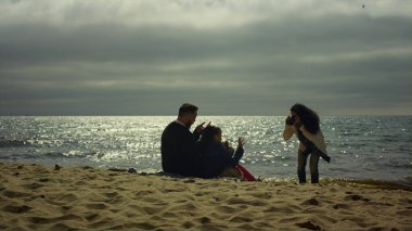 İnsanlar denizde plaj fotosferini birlikte severler. Aile fotoğraf çekiyor..