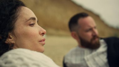 Deniz sahilinde saçlarına dokunan güzel bir kadın. Rahat çift doğa buluşmasının tadını çıkarıyor..