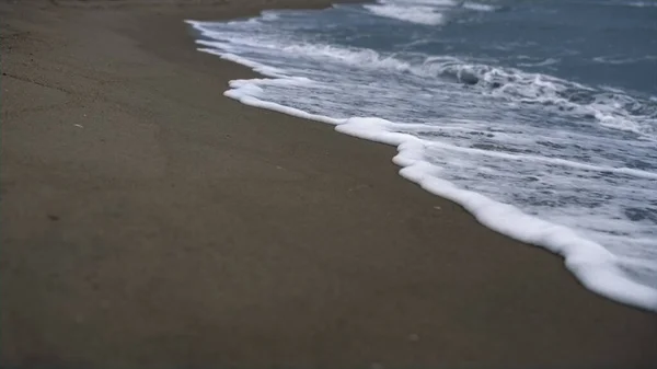 Onde sulla spiaggia che si infrangono sulla costa. mare schiuma tempesta blu riva natura fondo. — Foto Stock