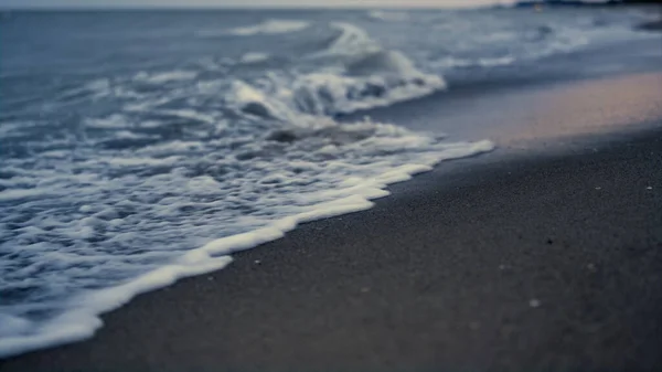 Onda do mar batendo areia no pôr do sol praia à noite. Oceano crepúsculo maré splash costa — Fotografia de Stock