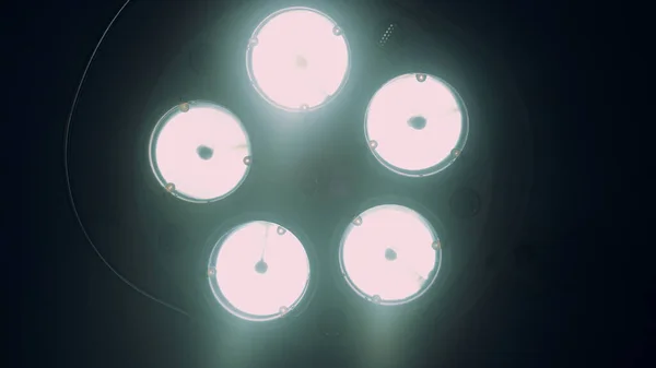 Ljus kirurgisk lampa släcks i mörka sjukhus operationssal på nära håll. — Stockfoto