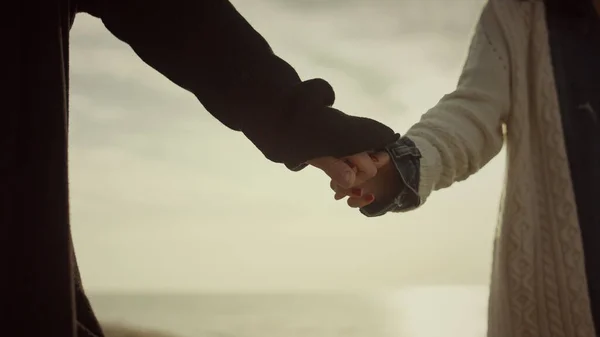 Любители свиданий держатся за руки на пляже на восходе солнца. Пара прикосновений снаружи. — стоковое фото