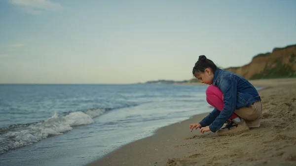 Cute girl gra piasek na plaży morskiej. Dzieciak cieszący się wakacjami na wybrzeżu przyrody. — Zdjęcie stockowe