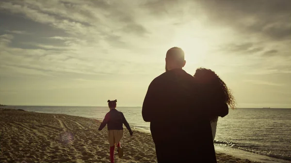 Υπέροχη οικογένεια αναζητούν ηλιοβασίλεμα θάλασσα παραλία. Μαμά μπαμπάς παιδί περπάτημα όμορφη ακτή. — Φωτογραφία Αρχείου