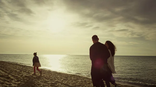 Relaksująca rodzina spacerująca po piaszczystej plaży o zachodzie słońca natura nieba. Ludzie lubią widok na morze.. — Zdjęcie stockowe