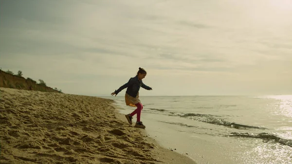 Söt unge som springer i land på morgonen. Lekfull flicka som går iväg strandvågor. — Stockfoto