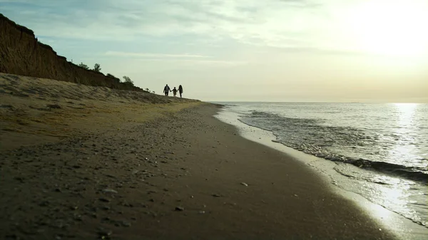 Rodzinna grupa spacerująca po plaży nad brzegiem morza. Fale rozbijają się na wybrzeżu oceanu. — Zdjęcie stockowe