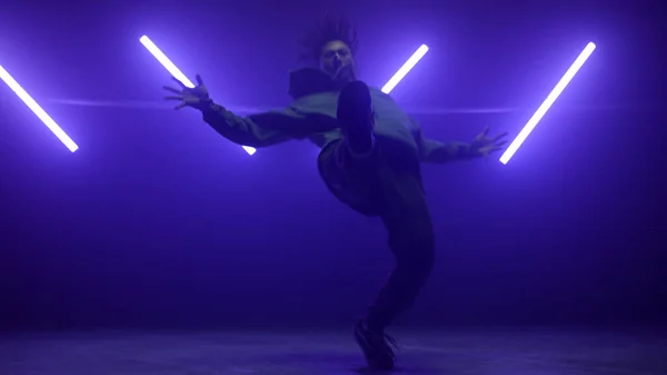 Hiphop performer faire des tours sur scène. Homme actif freestyling en ultraviolet. — Photo
