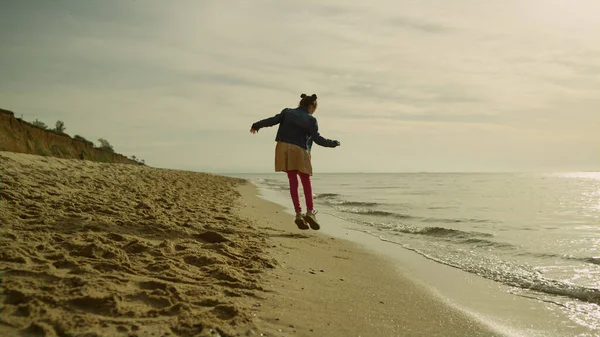 Criança menina jogando praia no mar natureza. Miúdo alegre pulando na linha de areia. — Fotografia de Stock
