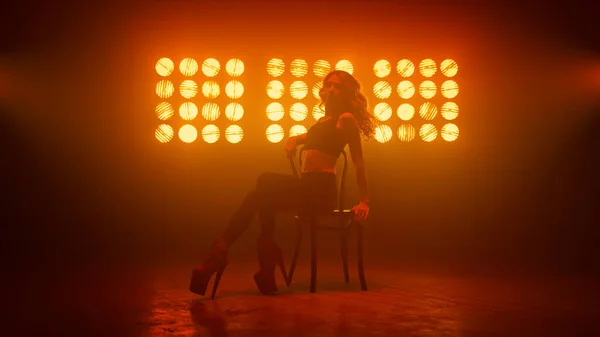 Дівчина показує еротичні рухи, що сидять на кріслі клубу. Гаряча танцівниця піднімає ноги . — стокове фото