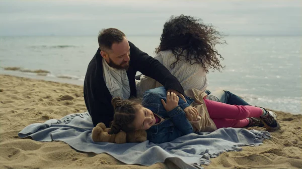 Joyful family group hugging on beach sand. Happy people cuddling by sea shore.