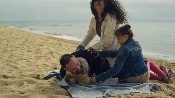 Neşeli ebeveyn çocuk deniz kenarında piknik yaparken eğleniyor..