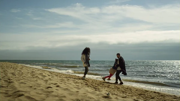 Neşeli bir aile deniz sahilinde güzel bir tatil yapıyor. Olumlu insanlar okyanusla oynar..