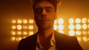 Gece kulübü ışıklarıyla sahnede poz veren bir adam vardı.. 