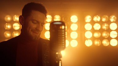 Sahnede solo gitar çalan bir adam. Olay yerinde enstrüman çalan adam.