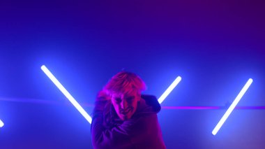 Modern stüdyo ultraviyole ışıkta ritmik hiphop hareketleri yapan adam.. 
