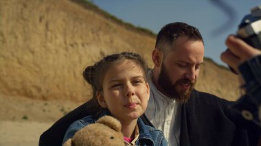 Babası sahilde gülümseyen bir kamera. Güzel bir aile fotoşopun tadını çıkarır..