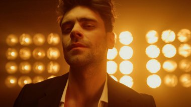 Seksi adam sahnede göz kamaştırıcıyı kirletiyor. Sahne ışıkları altında yürüyen erkek model..