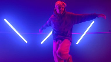 Neon arka ışıklandırmayla sokak dansı yapan adam. Şık break dansçı serbest stil seviyor..