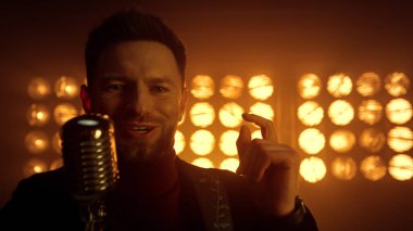 Sahnede mikrofon şakıyan yakışıklı adam. Gece kulübünde vokalist.