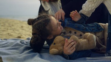 Deniz kumsalında aileyi oynayan gülen kız. Neşeli çocuk tatilin tadını çıkar..