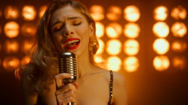 Çekici kız vokalist sahne gece kulübünde mikrofon tutarak şarkı söylüyor.