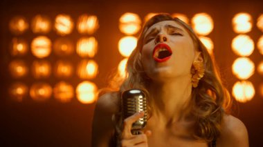 Sahnede tek başına şarkı söyleyen tutkulu bir şarkıcı. Sarışın vokalist gösteri yapıyor.